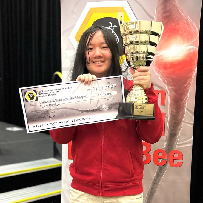 Lisa Wei, First Place Canadian National Brain Bee competition winner, holding trophy and prize.