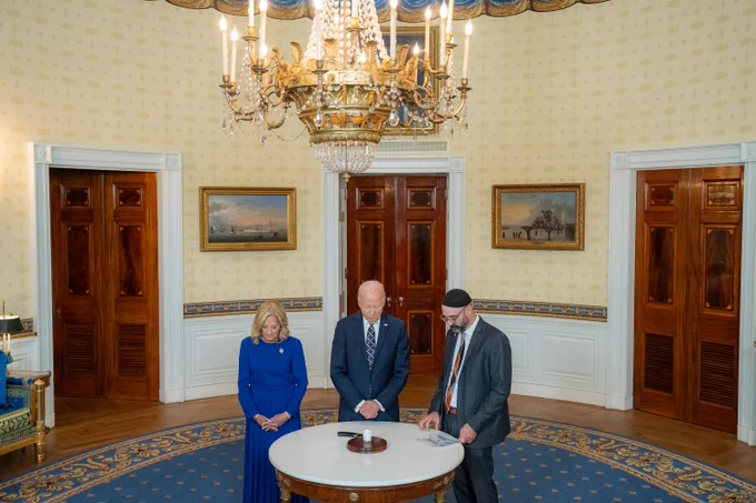 President Biden, the First Lady, and Rabbi Aaron Alexander light a yahrzeit candle in the Blue Room of the White House.