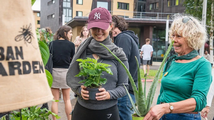 Smiling people at a house plant sale on campus.