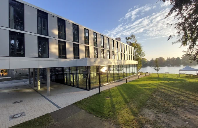 Building in a green environment on a sunny day, next to a lake. 
