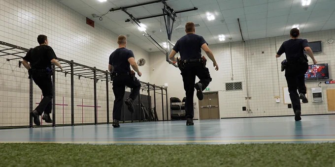 Four cadets can be seen running in a gym setting. 