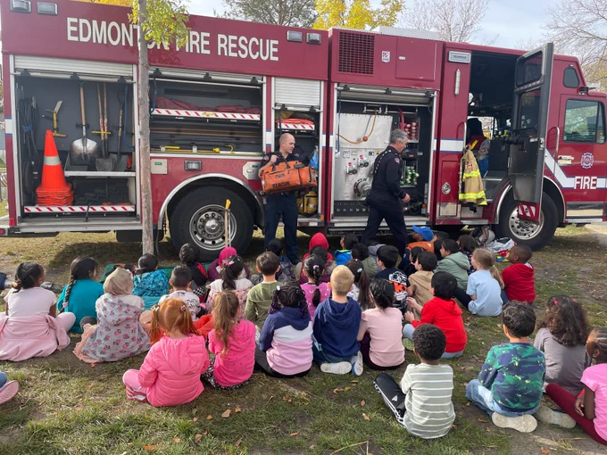 A firefighter and fire captain give an equipment demonstration to students.