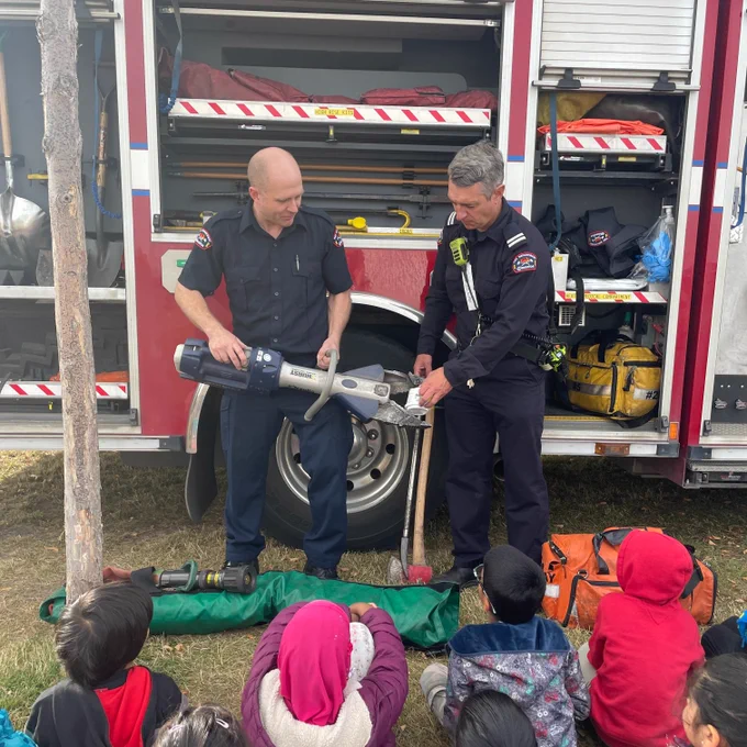 A firefighter and fire captain give an equipment demonstration to students.