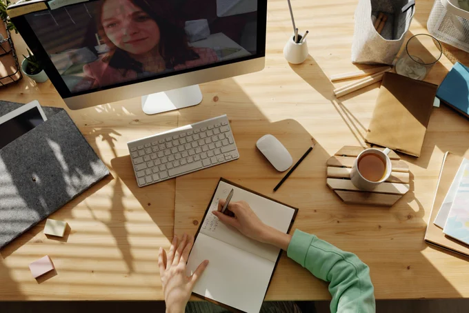 Aerial view of a person watching a woman on screen and taking notes