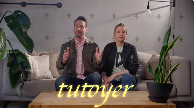 Two members of the Improtéine group sitting on a sofa, discussing the use of "tu" vs "vous" in French. The text reads "tutoyer."
