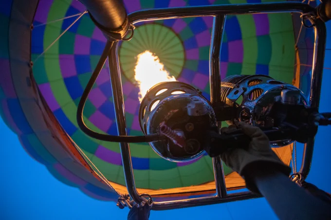 A close-up image from inside a hot air balloon, showing the burner flame heating the air to lift the balloon. 