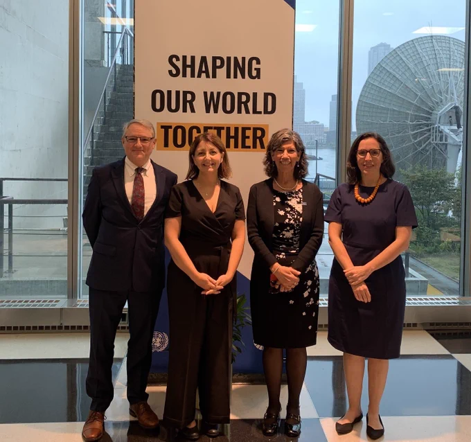 An image of CDC Director Dr. Mandy Cohen with CDC staff in front of a sign that reads Shaping our world together. 