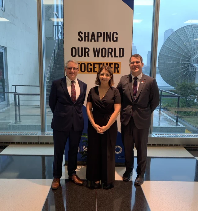 An image of CDC Director Dr. Mandy Cohen with CDC staff in front of a sign that reads Shaping our world together. 