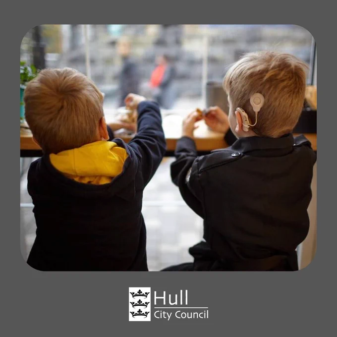 Two children are seated at a table, looking out a window. The image has a grey border, with the Hull City Council logo visible at the bottom.