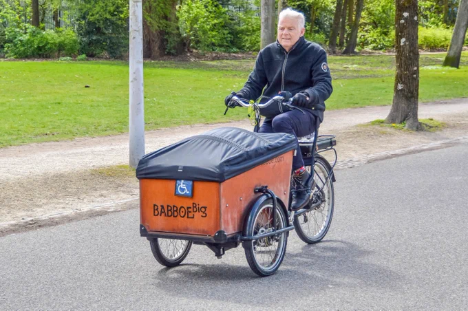 A senior cycling on a bakfiets in Amsterdam.