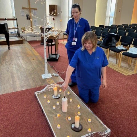 Photo of nursing staff lighting a candle at the memorial