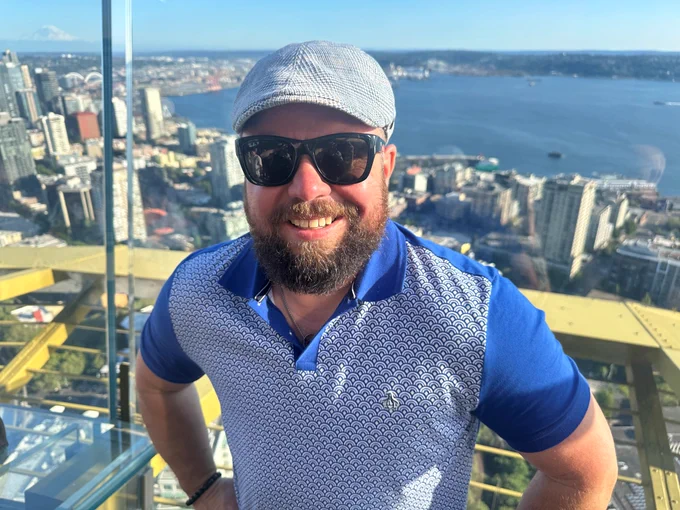 Gemma Hickey wearing a blue and white shirt stands in front of a beautiful skyline.