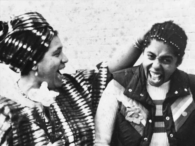 Audre Lorde teasing Barbara Smith about her braided hair, 1979. Photo by Tia Cross.