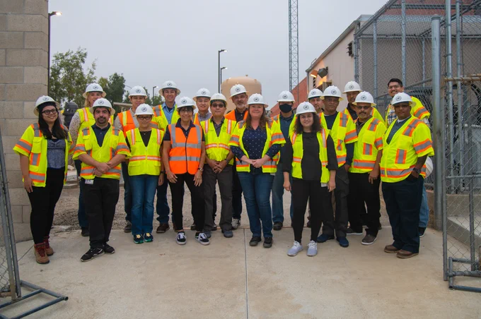 Group of PWP water professionals wearing hard hats and neon yellow high-visibility vests standing at a construction site.