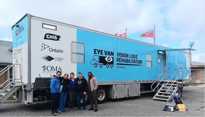 Picture shows 5 team members standing in front of the blue Vision Loss Rehabilitation Canada Eye Van. 