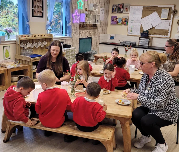 Children and adults sitting at a table eating