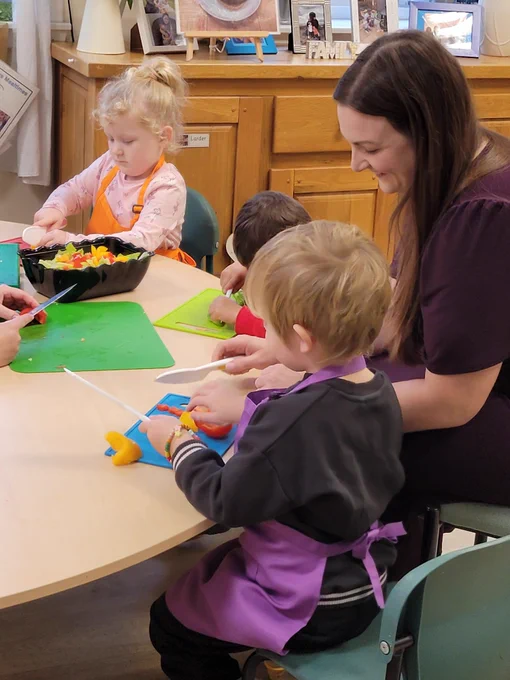 Adult and children sitting at a table chopping food