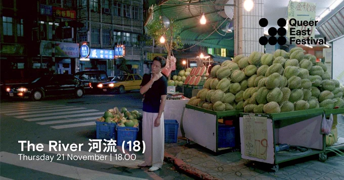 A person stands on a street corner at night next to a pile of durians for sale. Neon lights and storefronts are visible in the background, giving a night-time market atmosphere. The text in the lower left corner reads "The River 河流 (18), Thursday 21 November, 18.00." The logo of the "Queer East Festival" is in the upper right corner.