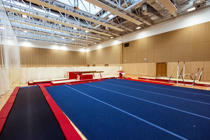 a gymnastics hall with various equipment on the floor