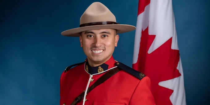 A graduation portrait of a man in red serge smiling at the camera.