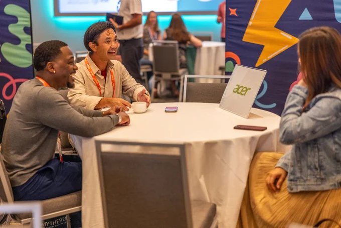 Four people sitting around a table engaged in a lively discussion at a tech conference.