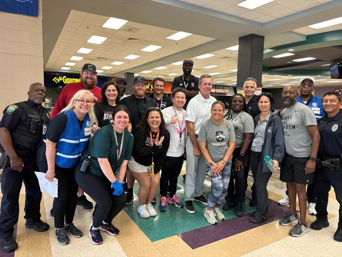 Group of people pose in school cafeteria used as evacuation shelter ahead of Hurricane Milton