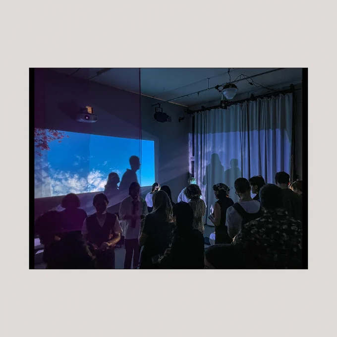 People stand in a darkened room watching a screen illuminated blue and purple. Image supplied by Composite.  