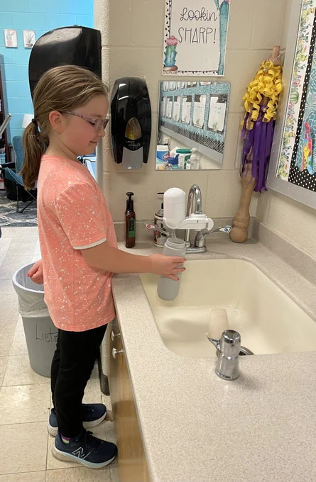 Girl filling a water bottle from a filtered faucet in a school. 