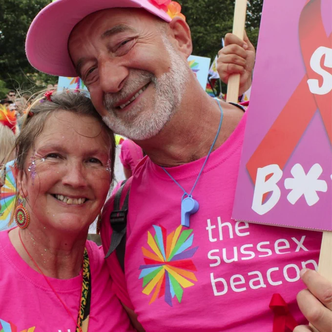 Two people wearing The Sussex Beacon t-shirts at Pride, they are smiling