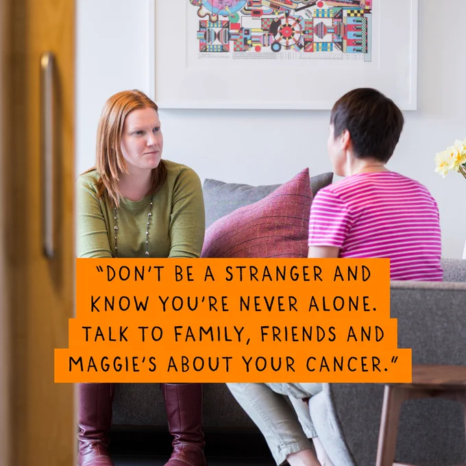 Two people are sitting opposite each other in a room, in mid-conversation. The quote on the image says, 'Don't be a stranger and know you're never alone. Talk to family, friends, and Maggie's about your cancer.'
