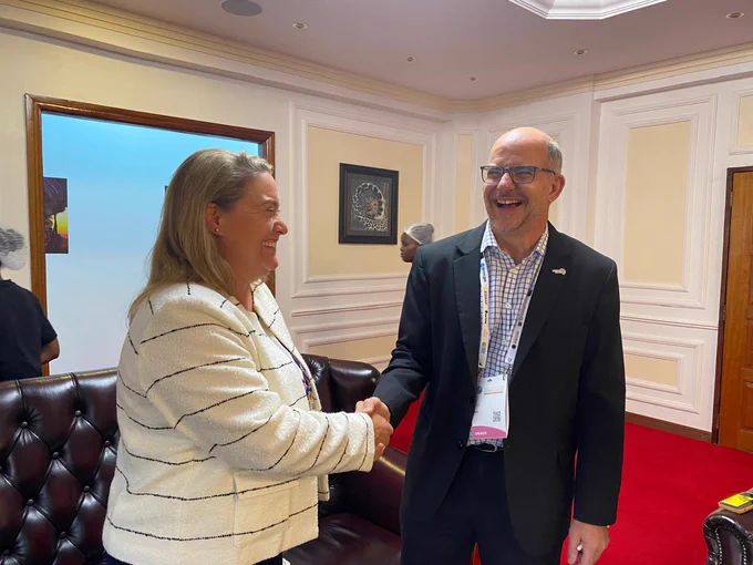 A man and a woman shaking hands while laughing.
