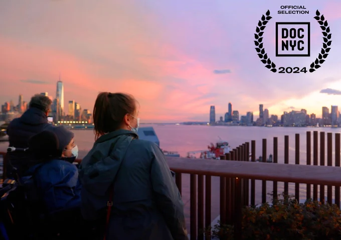 Samuel and his DSP Kaitlyn looking at the NYC skyline with a colorful sunset. In the top right corner is a black laurel for DOC NYC 2024.