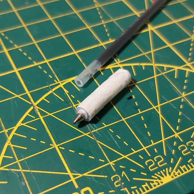 Photo of a crude plotter pen made out of a gel pen tip, tube from a bottle of bleach and masking tape.