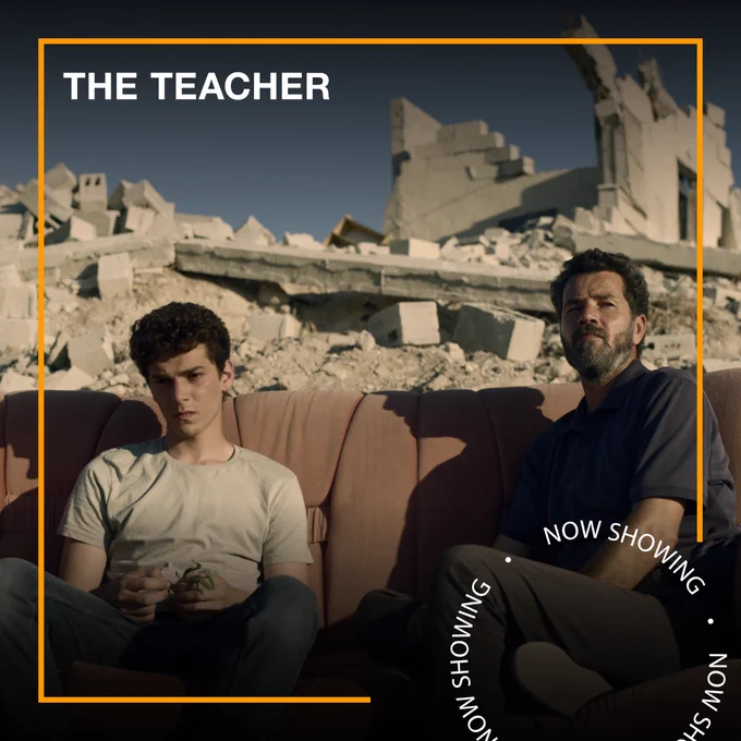 In a bombed area, two men sit on a sofa outside. Text - The Teacher, Now Showing