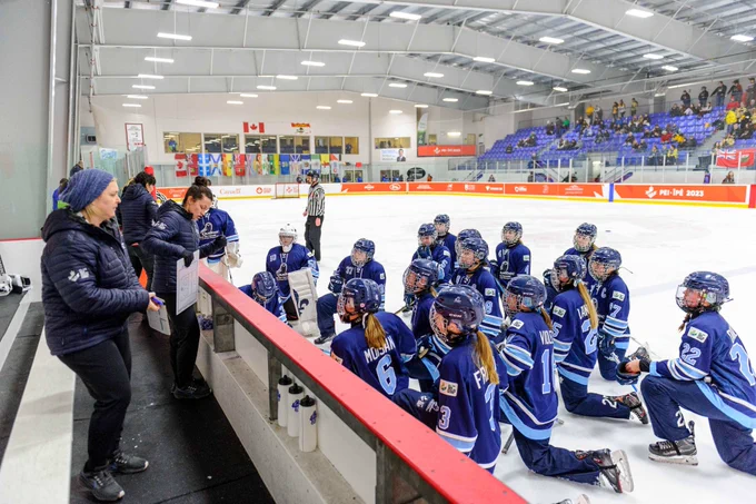 Alt text EN: A group of ringette players listening to their coaches.