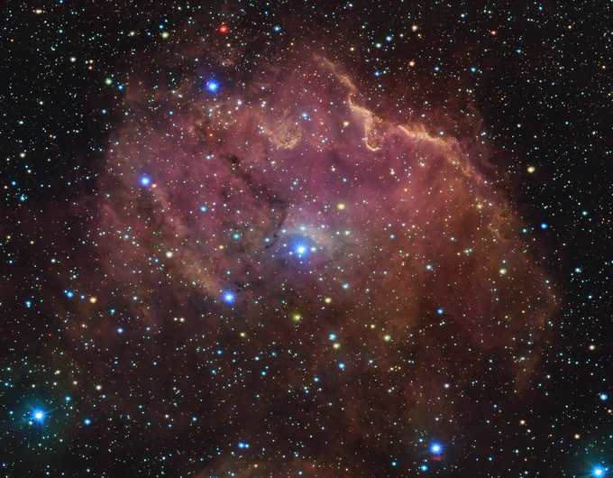 Emissionsnebel in Rot- und Brauntönen vor einem sternübersäten Hintergrund
