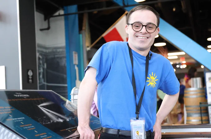 Craig smiles and stands on the exhibit floor of the children's museum ready to help patrons during his shift. 