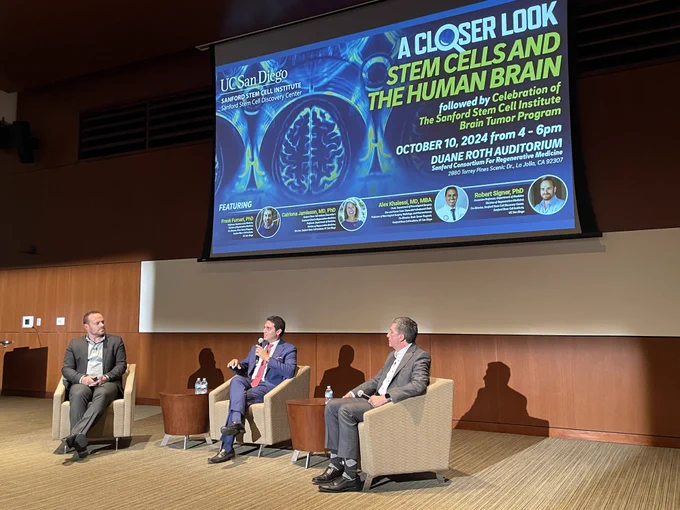 Three men discussing stem cells in front of a screen. 