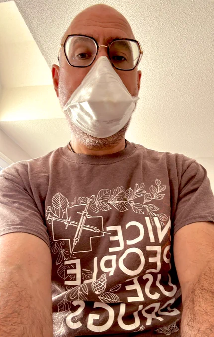 Man wearing glasses and a white n95 respirator and a shirt that says nice people use drugs