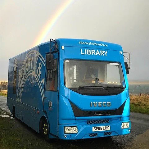 BookyMcBookface the Mobile Library parked in front of a rainbow