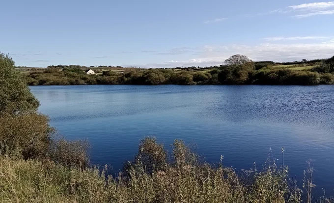Rippled water reflecting the blue of the sky, surrounded by green trees and fields