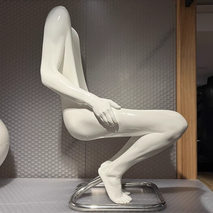 Side view of a chair designed in 1970 by Ruth Francken, currently on display at the Musée des Arts Décoratifs in Paris. It’s made of white polyurethane, and is shaped like a seated nude man with no head. The seat part is hollowed out of his chest and lap.