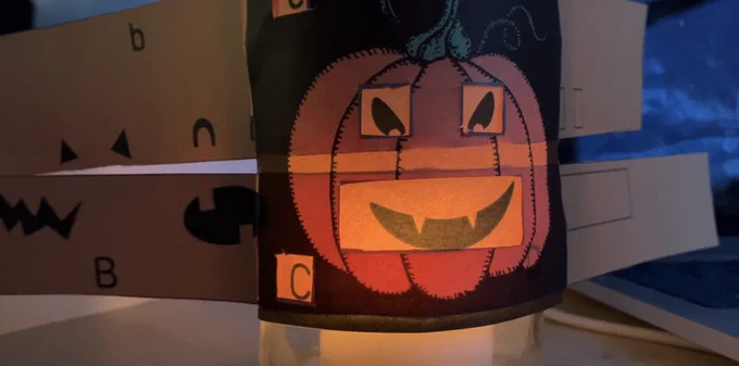 A still from the YouTube video showing the Program A Pumpkin version that uses a jam jar with a tealight behind it for an extra spooky glow.