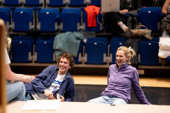 Rehearsal photo for Fy Enw i yw Rachel Corrie. A man and woman are sitting on the floor giggling.