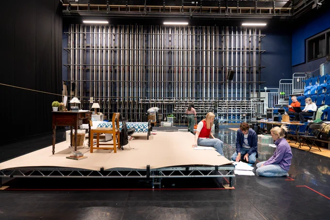 Rehearsal photo for Fy Enw i yw Rachel Corrie. A wide shot of the stage with people reading scripts and working.