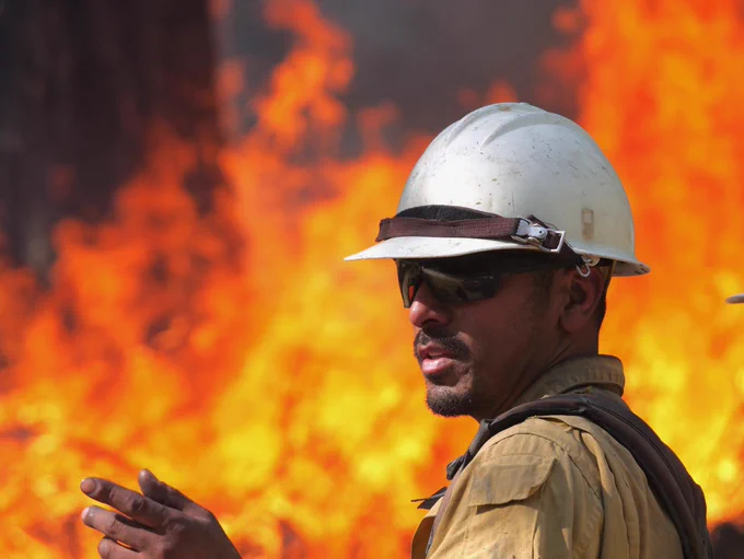 Boise Smoke Jumper Josh Rodriquez gives direction to a colleague during a burnout on the Goat Fire on Oct. 7. The picture was taken at a distance with a zoom lens, making the flames behind Rodriquez appear closer to him than they actually are. Photo by Public Information Officer Andy Lyon.
