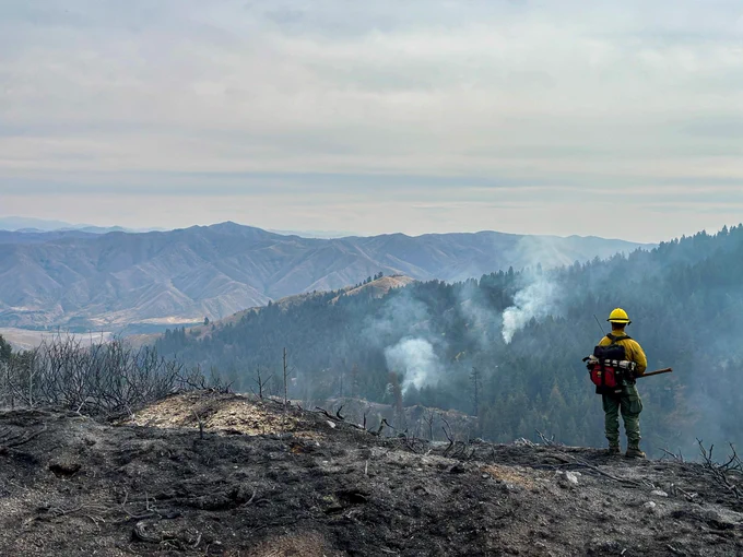 Firefighter on ridge looking down at smoke in timber from Valley Fire.