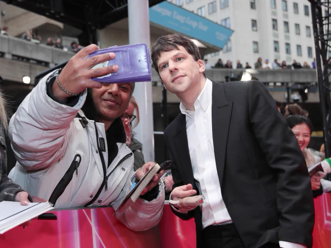 Jesse Eisenberg taking a selfie with a fan.