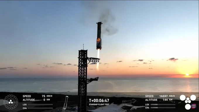 Superheavy booster coming back to the tower, slowing under its thrust. To the right the morning Sun is visible over the ocean.