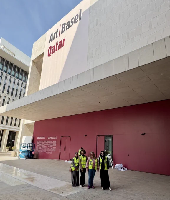 Group photo of students and faculty in front of signage saying art Basel qatar